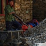 A-young-builder-working-with-newer-method-of-building-house-lodging-gravel-into-wheelbarrow-seen-during-Tamang-hertiage-circuit-trek