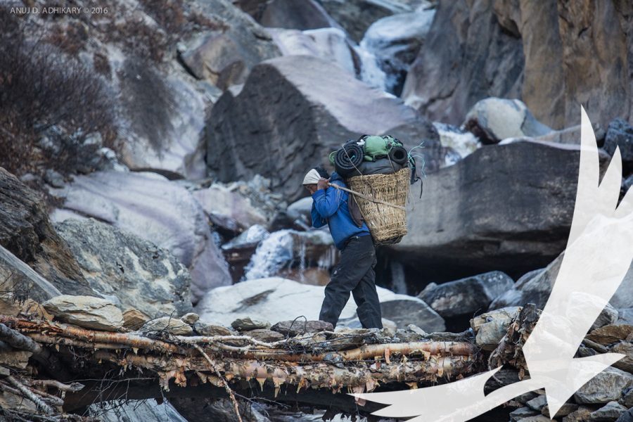 A porter walks across a makeshift bridge over a frozen river Dolpo Photo by Anuj Adhikary - Upper Dolpo To Jomsom
